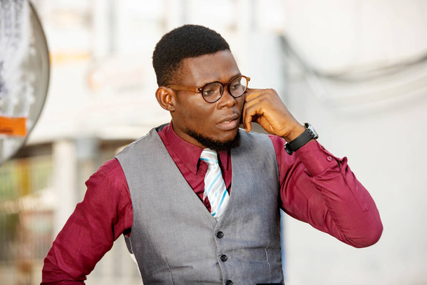 молодий бізнесмен стоїть на відкритому повітрі, розмовляючи на мобільному телефоні
. - Фото, зображення