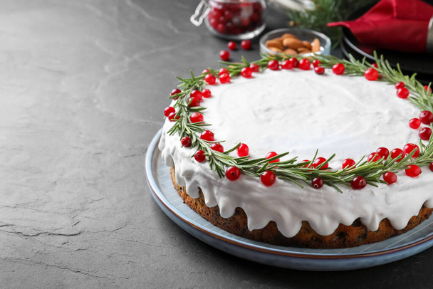 Traditional Christmas cake decorated with rosemary and cranberries on dark grey table, space for text - Fotografie, Obrázek
