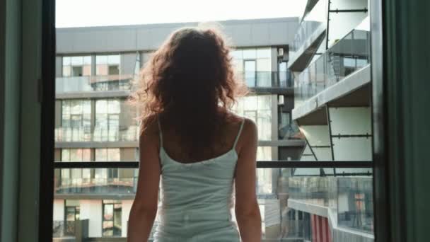 Genç ve güzel bir kadın dairesinin balkonuna çıkıyor. 4K - Video, Çekim