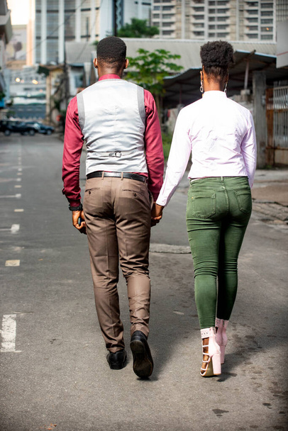 vista trasera de una hermosa pareja de jóvenes africanos caminando en la calle al aire libre - Foto, imagen