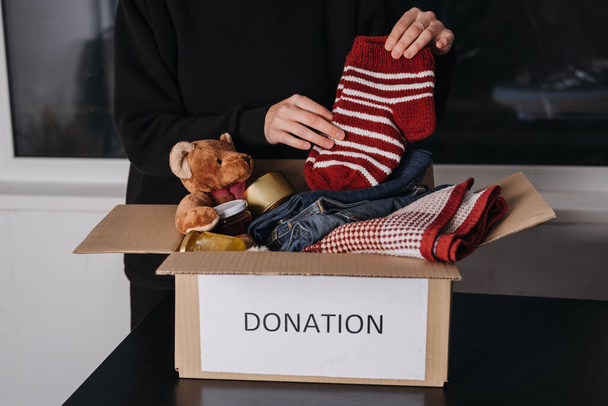 Коробка пожертвувань, благодійні подарунки перешкоджають, допомагають біженцям та бездомним. Різдвяна Різдвяна благодійна подарункова коробка з теплим одягом, їжею та іграшками вдома. Благодійність, що дає зимові перешкоди сім'ям, які потребують допомоги
 - Фото, зображення