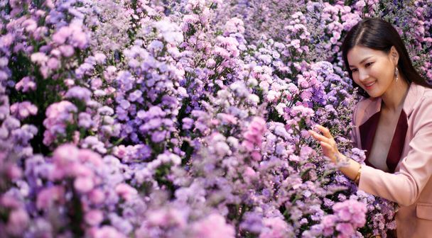 Piękna Azjatka w biznesie Pink Suit relaksuje się w tysiącach kwiatów pola w godzinach przerwy od pracy, chill out concept copy space, selektywne skupienie - Zdjęcie, obraz