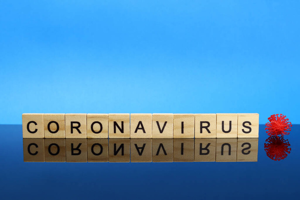 Coronavirus λέξη από ξύλινα γράμματα σε μια επιφάνεια καθρέφτη. Έννοια f του ιού Covid-19 ή 2019-ncov. - Φωτογραφία, εικόνα