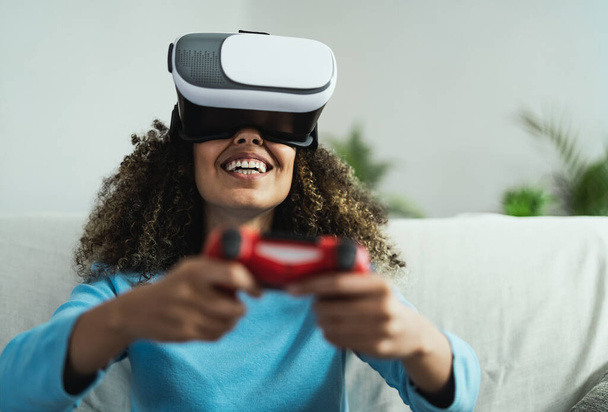 Young African woman playing online video games - Happy gamer having fun on new technology console with virtual reality experience - Youth millennial lifestyle and technology concept - Photo, Image