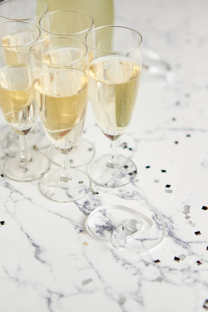 Copos de champanhe e garrafa colocada sobre fundo de mármore branco - Foto, Imagem