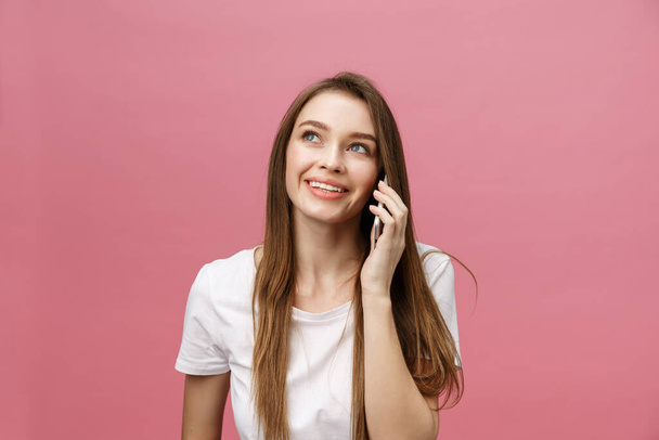 Veselá mladá žena mluví na mobilním telefonu izolované na růžovém pozadí - Fotografie, Obrázek
