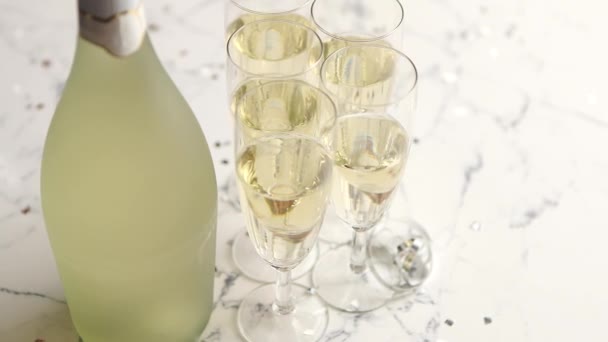 Champagne glazen en fles geplaatst op witte marmeren achtergrond - Video