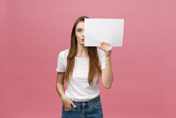 Νεαρή καυκάσια γυναίκα κρατώντας λευκό φύλλο χαρτιού πάνω από απομονωμένο υπόβαθρο φοβάται σε κατάσταση σοκ με ένα πρόσωπο έκπληξη, φοβάται και ενθουσιασμένος με την έκφραση του φόβου - Φωτογραφία, εικόνα