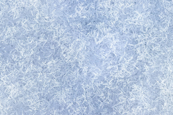 Bovenaanzicht van sneeuwkristallen verlicht door zonlicht, van dichtbij geschoten. Winterachtergrond. - Foto, afbeelding