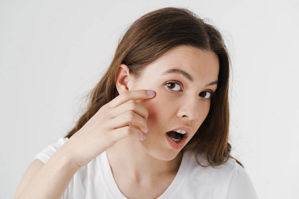 Schockierte junge Frau mit Hautproblemen vor weißem Hintergrund - Foto, Bild