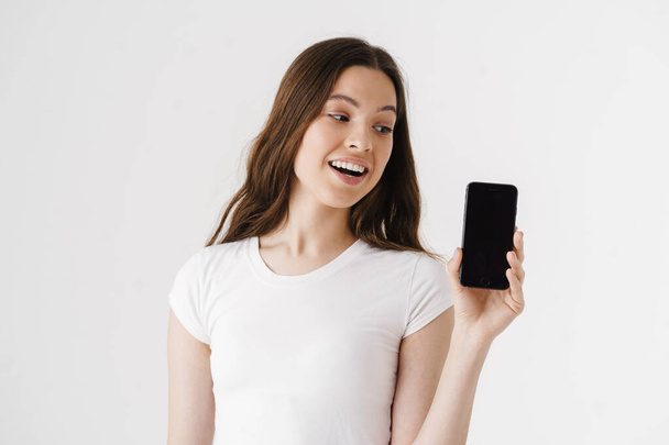 Portrait of a happy casual woman showing blank smartphone screen isolated on a white background - Fotoğraf, Görsel