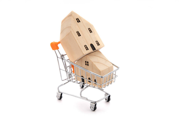 2 wooden house models in shopping cart isolate on white background. - Photo, Image
