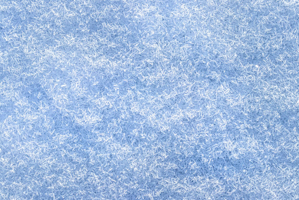 Bovenaanzicht van sneeuwkristallen verlicht door zonlicht, van dichtbij geschoten. Winterachtergrond. - Foto, afbeelding