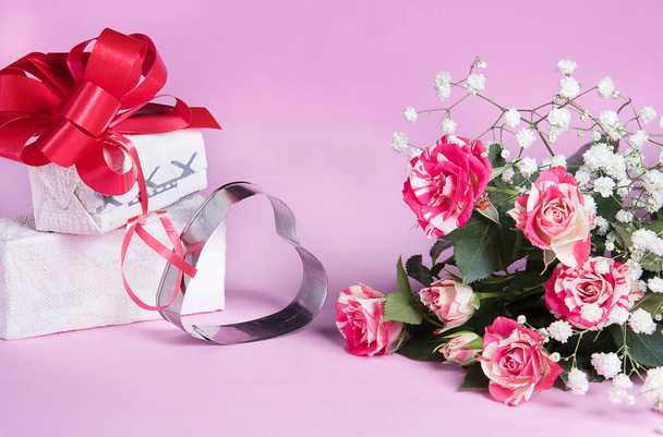 Decorative metal heart, red rose bouquet and gift box, greeting card on pink background. Holiday congratulations concept.  - Photo, Image