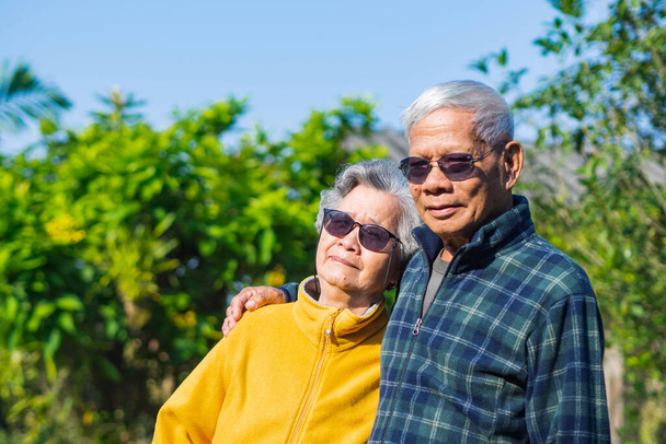 Retrato de una romántica pareja de ancianos asiáticos sonriendo y mirando a la cámara mientras están de pie en un jardín. Pareja mayor. Concepto de personas mayores y asistencia sanitaria. - Foto, Imagen
