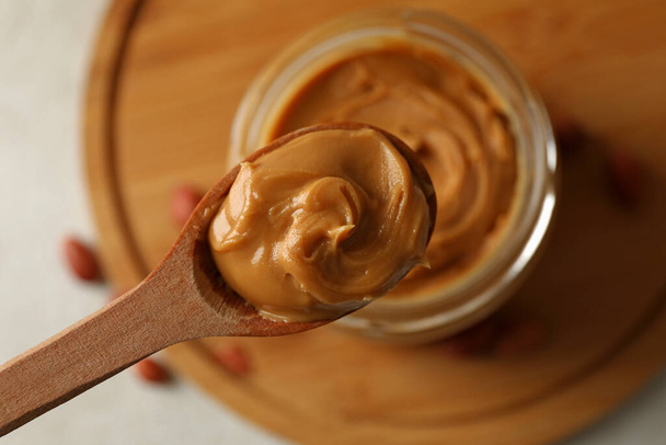 Colher e jarra com manteiga de amendoim, close-up - Foto, Imagem