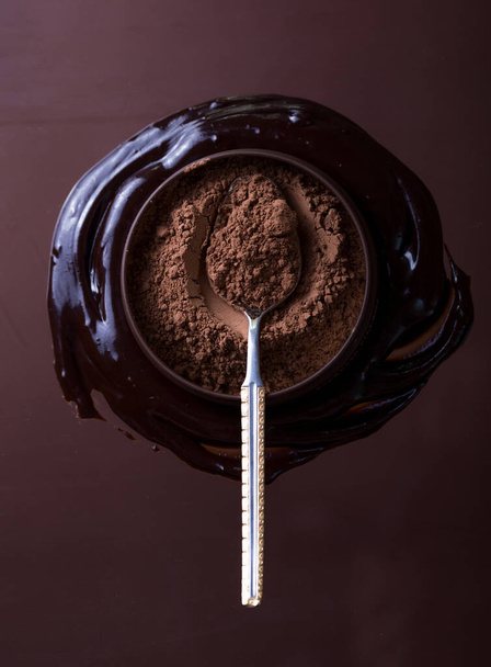 cacao en polvo en tazón con granos de cacao en papel pintado marrón - Foto, Imagen
