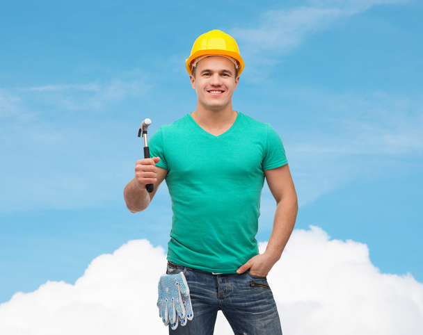 Smiling manual worker in helmet with hammer - Foto, afbeelding