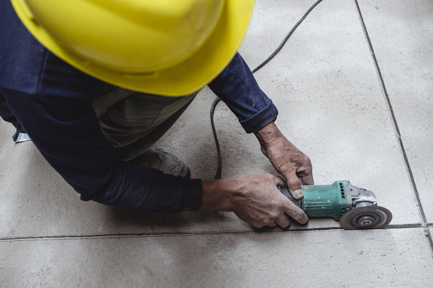 Rakennustyöntekijä käyttää kulmahiomakonetta saadakseen betonilattian. Luominen laatta kuvio pinnalle. - Valokuva, kuva