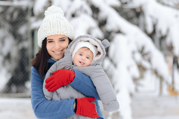 Happy Mother Holding Baby Enjoying Snow in Wintertime - Fotografie, Obrázek