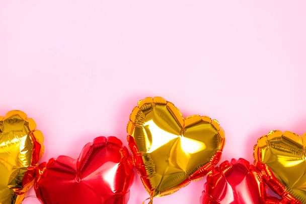 Frame voor tekst met rode en gouden harten folie ballonnen bovenaanzicht op roze Valentijnsdag achtergrond. Kopieerruimte - Foto, afbeelding