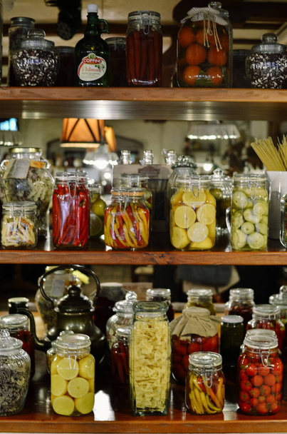 Фон запасов продуктов питания в стеклянных банках. Много ярких банок с маринованными овощами и фруктами - Фото, изображение