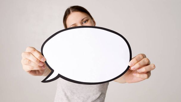 mid adult woman holding blank speech bubble on white background. Horizontal shape, front view, waist up, copy space - Photo, Image