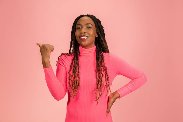 Portrait of young african-american woman isolated on pink studio background, facial expression. Beautiful female half-lenght portrait with copyspace. - 写真・画像