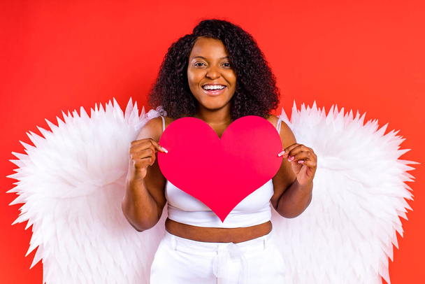 espagne ange joyeux avec des ailes tenant forme de coeur en studio rouge - Photo, image