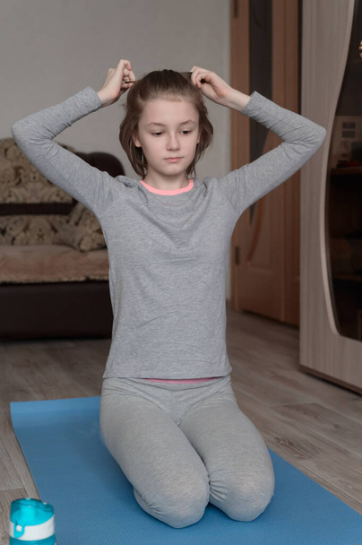 Teenage girl doing fitness exercise, practicing yoga at home. Healthy lifestyle concept. Workout at home. Home interior, daytime. - Photo, Image