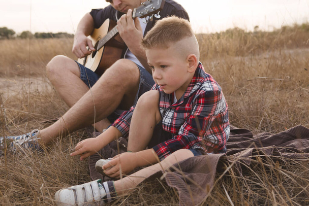 fMan and son having fun in summertime. ather and son playing guitar in the park - Fotografie, Obrázek