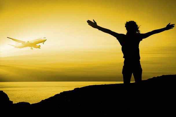 Mujer en la isla agitando sus brazos al avión volador durante el atardecer - Foto, imagen