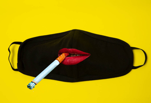 Αφηρημένη μαύρη ιατρική μάσκα με χείλη και τσιγάρο σε χρωματιστό φόντο. Minimal χρώμα νεκρή φύση και φανταχτερή φωτογραφία - Φωτογραφία, εικόνα