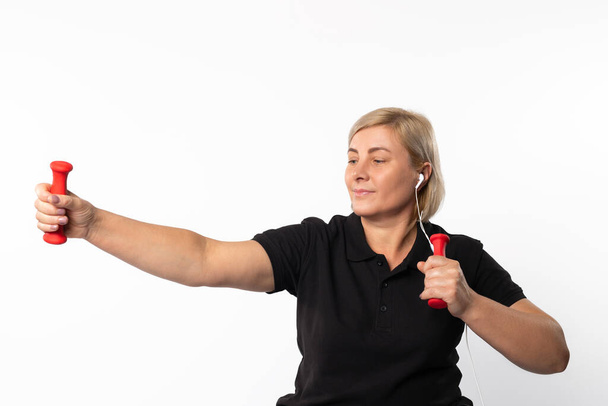 A woman goes in for sports at home in headphones with dumbbells. Photo on a white background. High quality photo - Zdjęcie, obraz