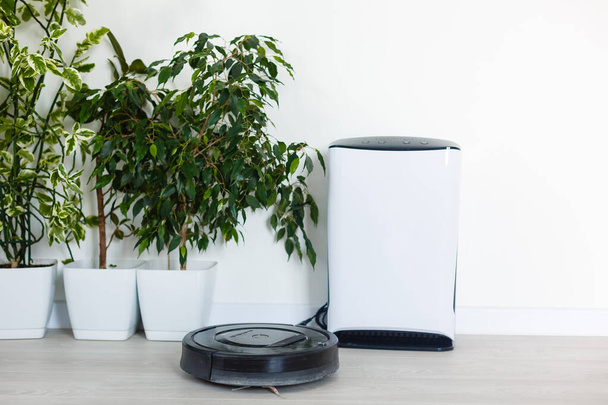 Robot aspiradora y purificador de aire trabajando en el hogar moderno - Foto, Imagen