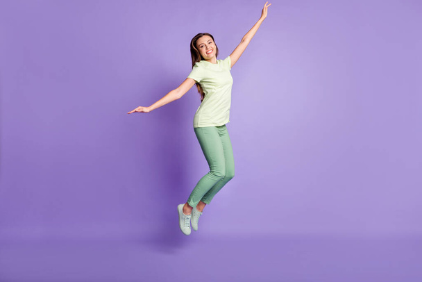 Full body photo of charming person jump arms flying wear light green outfit isolated on violet color background - Фото, зображення