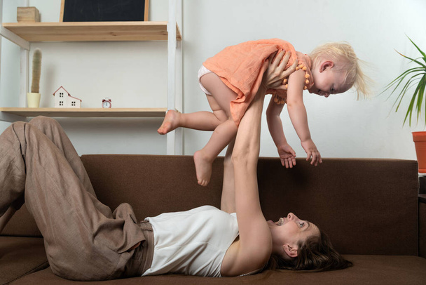 Mom plays with her daughter and raises her above her. Fun at home. - Фото, зображення