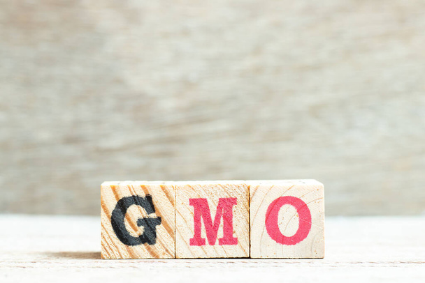 Blok liter alfabetu w słowie GMO (skrót od organizmów zmodyfikowanych genetycznie) na tle drewna - Zdjęcie, obraz