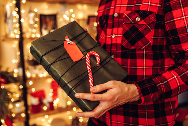 Christmas young man, in a plaid shirt, with a Christmas present at home in a Christmas interior, Christmas, holiday - Foto, Bild