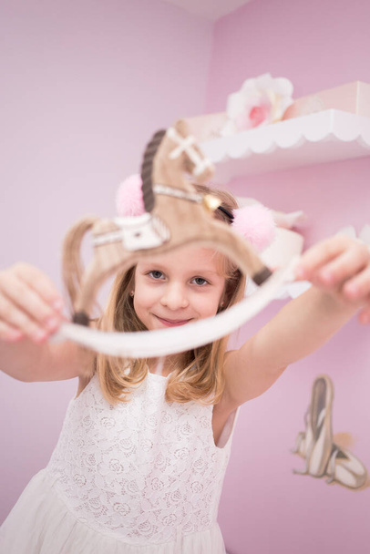 Little blonde girl showing off her birthday gift, pony toy - Foto, Imagem