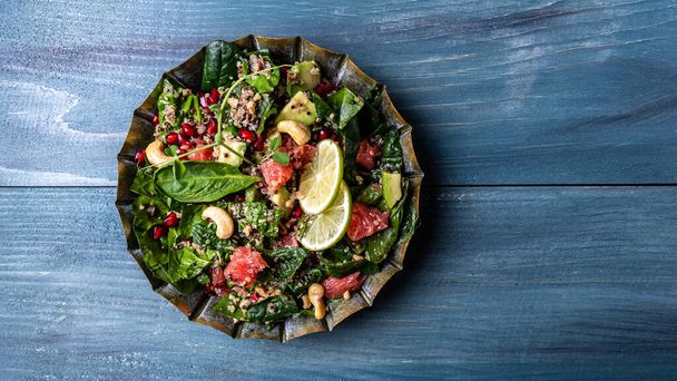 Trendy food - avocado salad with quinoa, spinach, grapefruit, pomegranate, nuts and microgreens. vegetarian recipe. healthy lunch dish. banner, catering menu recipe place for text, top view. - Photo, Image