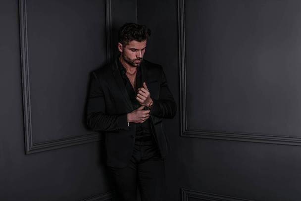 Handsome stylish man in elegant suit standing , posing on dark black background.  - Photo, image