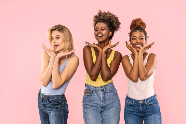 Funny photo of three multiracial women posing on pink studio background, smiling and having fun together. Happy lifestyle concept. - Foto, Imagem