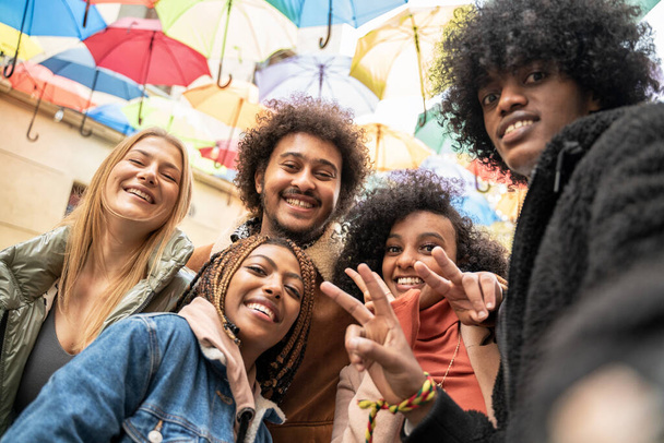 Multiracial group of friends taking selfie, looking at camera, having fun together in the city. Three young women and two men wearing casual clothes enjoying sunny day.  - Φωτογραφία, εικόνα