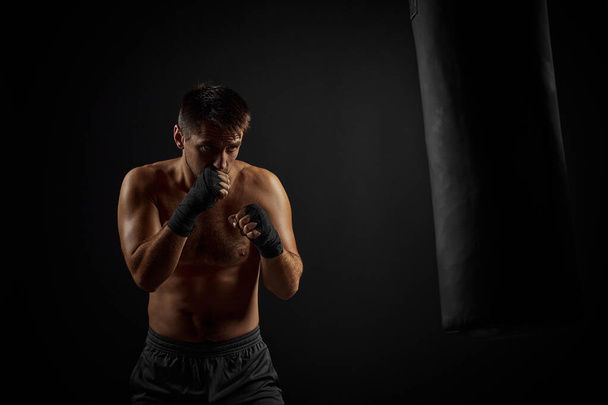 Male boxer punching in boxing bag - Foto, Bild
