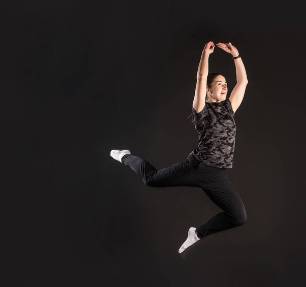 Fitness jumped. Engaged in sports on a black background Beautiful with a beautiful smile - Foto, afbeelding