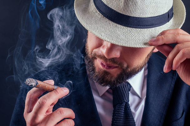 Portrait of an attractive business man with a cigar in black background studio - Zdjęcie, obraz