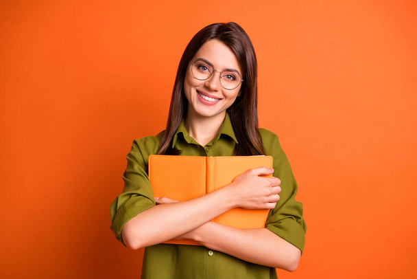 Photo portrait of cute lovely brunette girl holding embracing book smiling isolated on vibrant orange color background - Φωτογραφία, εικόνα