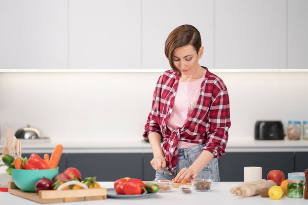 Cooking at home for loving family. Pretty young woman cutting ingredients on table cooking a lunch or dinner standing in the kitchen. Healthy food living. Healthy lifestyle - Foto, Imagem