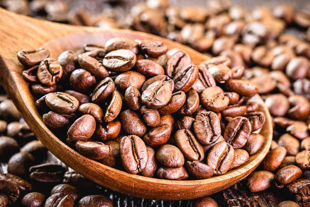 cuillère en bois rustique avec grains de café arabica torréfiés, éparpillés sur la table. Préparation de café cappuccino - Photo, image